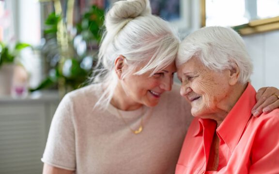 Elderly woman and daughter sharing a joyful moment at home
