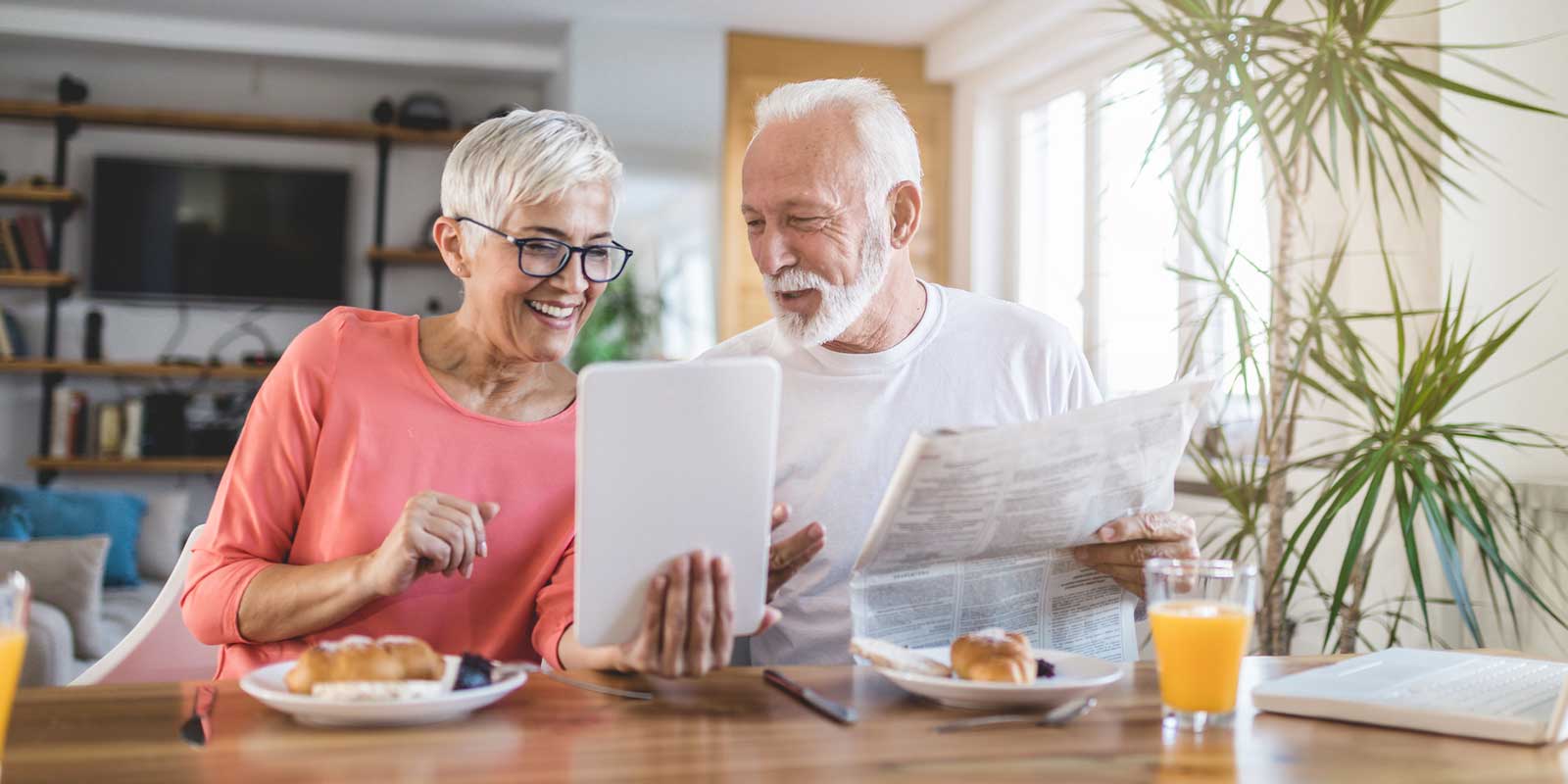 Man and woman reading the news at the breakfast table